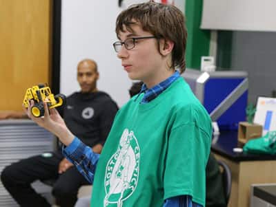 A student at Madeline English School showing the robot he assembled at the school's new technology lab.