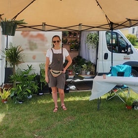 Tara Yonce standing in front of her work truck surrounded by plants