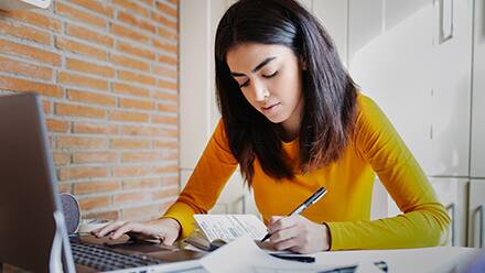 A woman in a yellow shirt working on her college capstone project