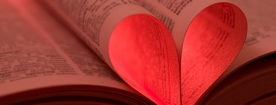 Two book pages coming together to create a heart shape with a red light through it