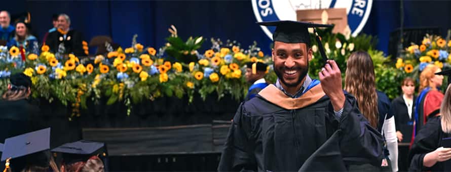 SNHU graduate student smiling in cap and gown at commencement ceremony