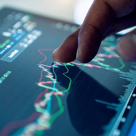 A hand hovering over a screen with a graph and different types of data on it showcasing what business analytics is