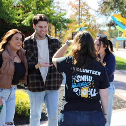 Four members of the SNHU community catching up at the Homecoming Street Fair