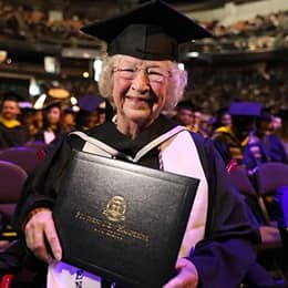 Annette Roberge, a 2024 graduate of SNHU, dressed in a graduation cap and gown and holding her diploma.