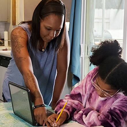 Latisha Aguilar '21, an SNHU graduate with a bachelor's in psychology, helping her daughter with homework at the kitchen table 