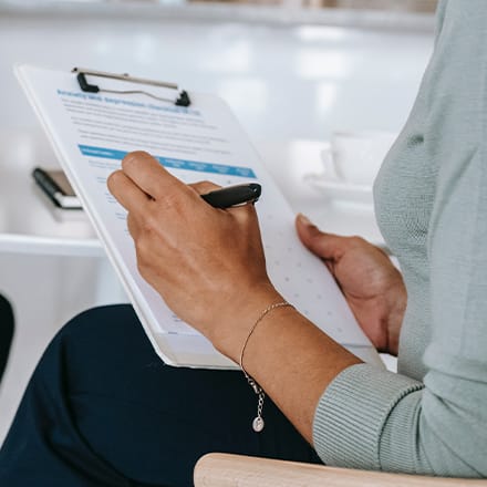 A clinical mental health counselor taking notes on a clipboard.