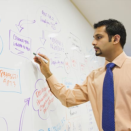 Man writing on white board putting his quantitative and qualitative data analysis skills into practice