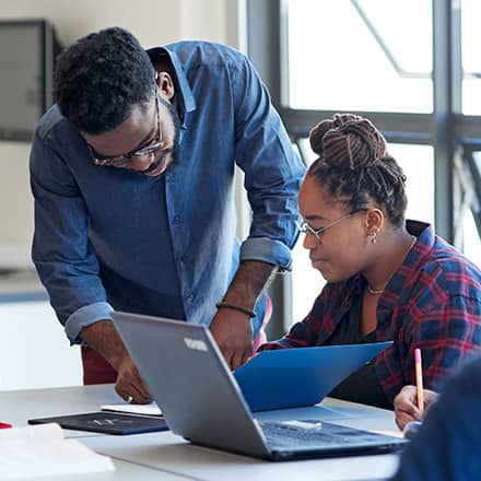 An instructor exhibiting qualities of a good teacher while helping a student review a document.