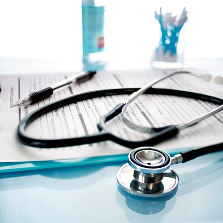 A stethoscope laying on a medical clipboard in a doctors office.