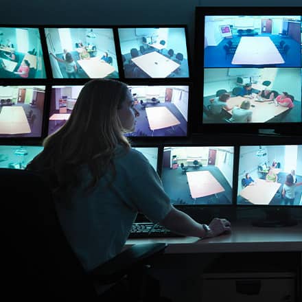 A homeland security professional monitoring a series of security camera feeds.
