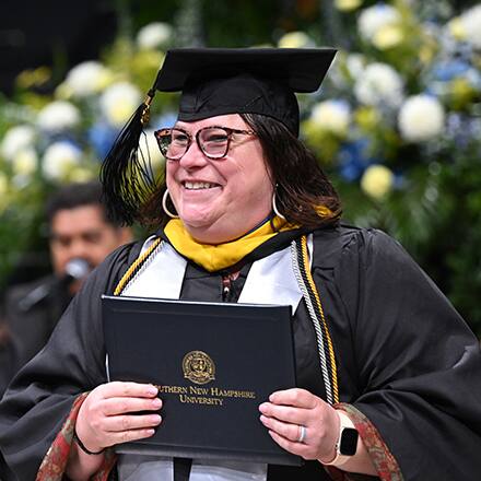 An SNHU graduate at Commencement earning their degree