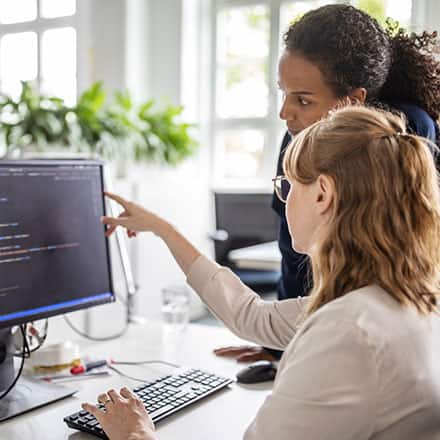 A woman points at a computer screen and gives advice on how to become a web developer