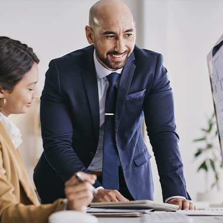 Two people in finance and accounting job roles, reviewing data on a computer.