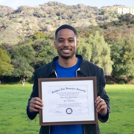 Keyon Tuiteleleapaga holding his SNHU diploma after earning a master's degree in psychology in 2024