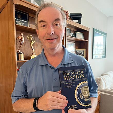 Anthony Knopps, an SNHU communication adjunct, holding his latest book, "The No-Fail Mission."