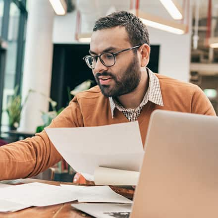 A professional considering master’s degree programs while sorting through documents at a table.