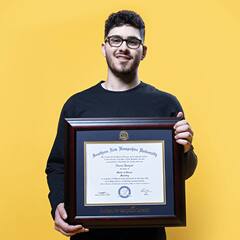 Naeem Jaraysi, holding his framed SNHU diploma after earning his master's degree in marketing in 2020.