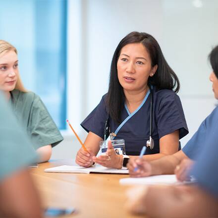 A group of nurses sitting around a table in a meeting