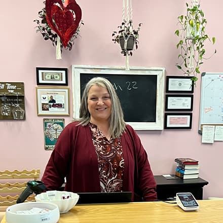 Heather Wejroch '23, an SNHU bachelor's in business administration graduate, standing behind the counter in Pages and Grapes.