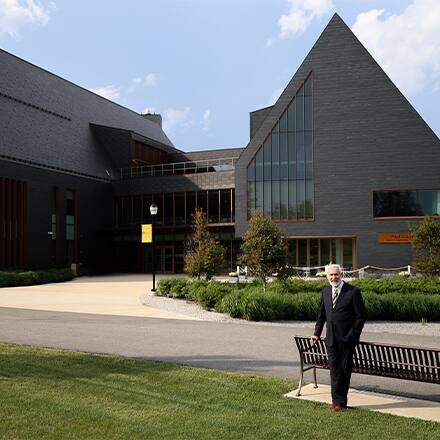 SNHU President Paul LeBlanc standing in front of the campus SETA facility, now named the Paul J. LeBlanc Hall.