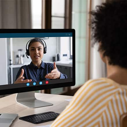 An academic advising sitting at their desktop in a video call with a student.