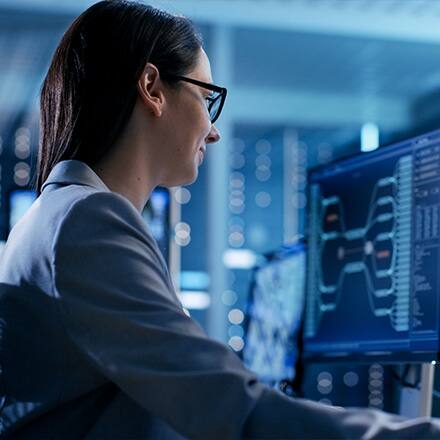 A woman sitting at a desktop working on information security 