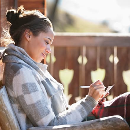 A woman on her deck practicing self-care by journaling.