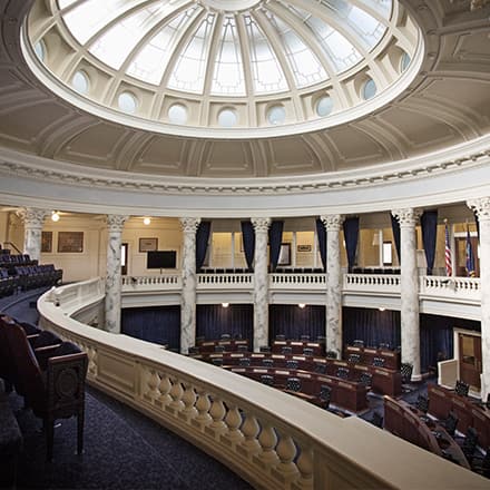 The interior of the U.S. Congress viewed from above showing dark brown wooden seats and marble columns.