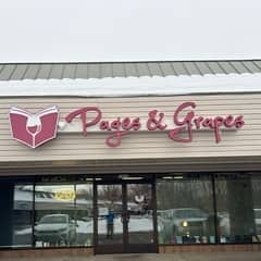 The outside of the bookstore Pages and Grapes with a big pink sign that says Pages and Grapes.