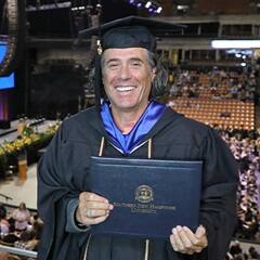 John Reck dressed in a graduation cap and gown after earning his bachelor's in graphic design at SNHU in 2022