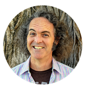 Larry Burns, a California resident and adjunct humanities instructor at SNHU, smiling in front of a tree.