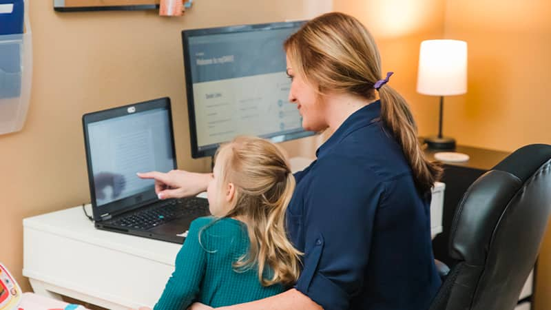 An SNHU Graduate sitting at a desk with a child