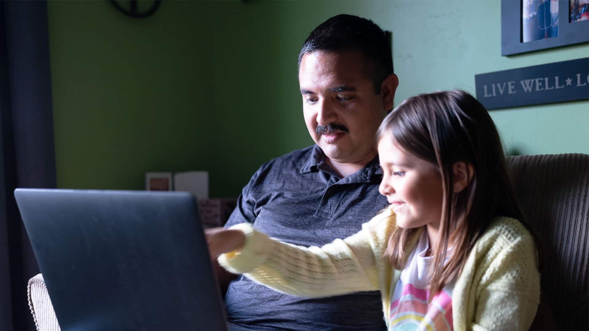 Salvador Villa, who earned a degree in criminal justice in 2019, and a young girl sitting on a couch looking at a laptop.