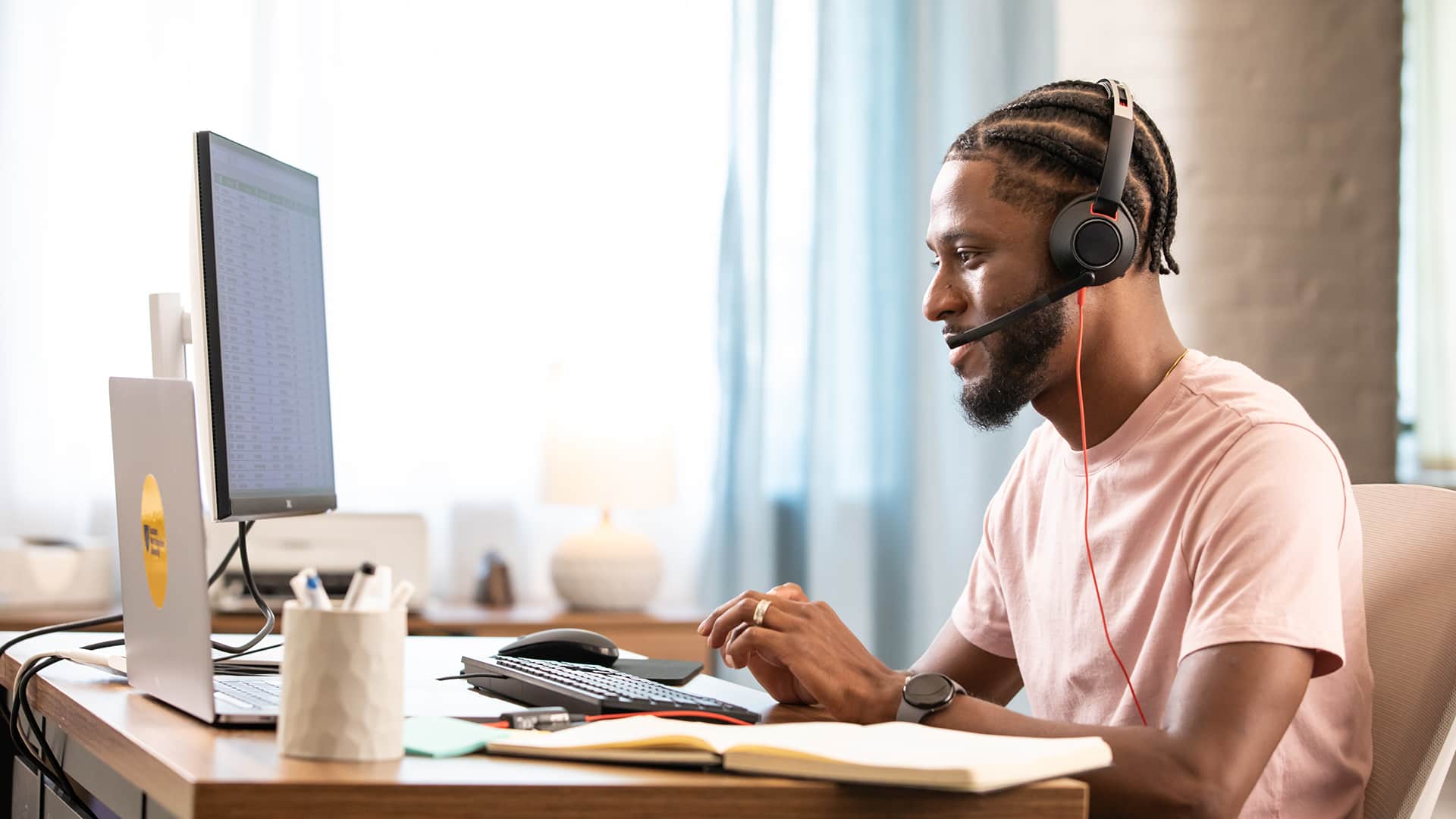 Matt Seawright, who earned a degree in operations and supply chain management in 2019, working on his laptop at a desk and wearing a headset including headphones and microphone.