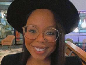 Kassandra Mack, who earned her degree in psychology with a concentration in child and adolescent development in 2021, smiling and wearing a large brimmed hat