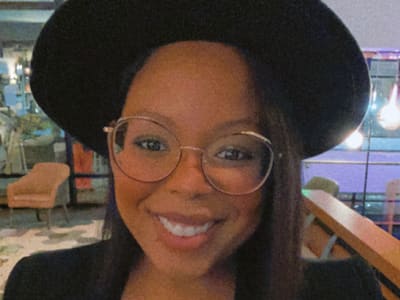 Kassandra Mack, who earned her degree in psychology with a concentration in child and adolescent development in 2021, smiling and wearing a large brimmed hat.