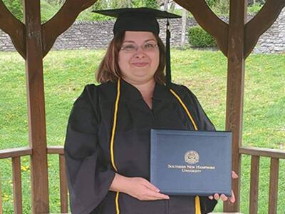 SNHU graduate Tabitha Tillery wearing her cap and gown and holding her diploma.