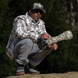 Ryan Carter, wildlife photographer, holding a long lens camera in a wooded setting.