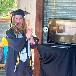 Samantha Sherwood '24, an SNHU graduate, in a cap and gown celebrating her name being called at SNHU's virtual Commencement.