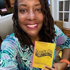 Dr. Kendra Thomas, senior director of people experience and belonging at SNHU, holding a book