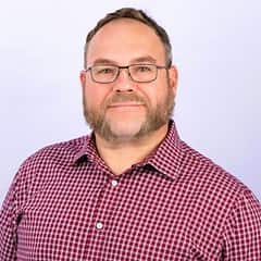 Thomas D. Leary IV, EdD, assistant vice president of learning solutions at SNHU, wearing a red and white checkered shirt.