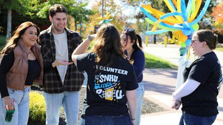 Five members of the SNHU community catching up at the Homecoming Street Fair