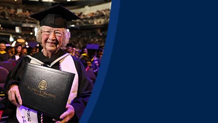 Annette Roberge, a 2024 graduate of SNHU, dressed in a graduation cap and gown and holding her diploma.