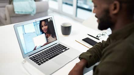 Two teammates collaborating on a school project through a video call made on a laptop.