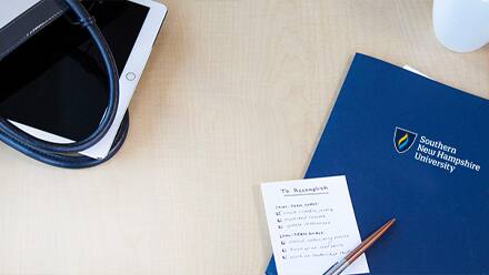 A blue SNHU folder and a pad of paper with a to-do list nearly complete