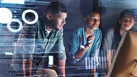 Three professionals with computer science degrees reviewing code on a computer monitor.