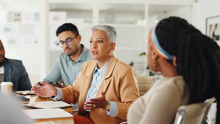 Four colleagues sitting at a meeting table, practicing conflict resolution skills.