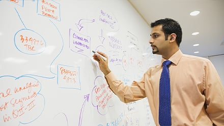 Man writing on white board putting his quantitative and qualitative data analysis skills into practice