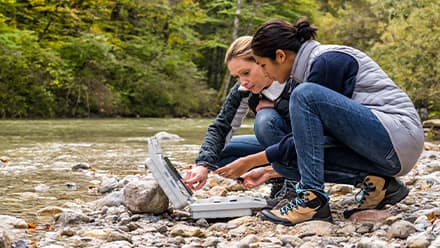 Two environmental science students working along the side of a river