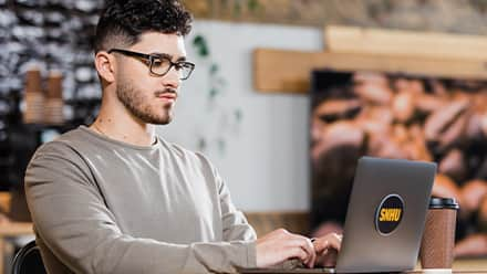 Naeem Jaraysi using a laptop to earn his marketing degree at SNHU